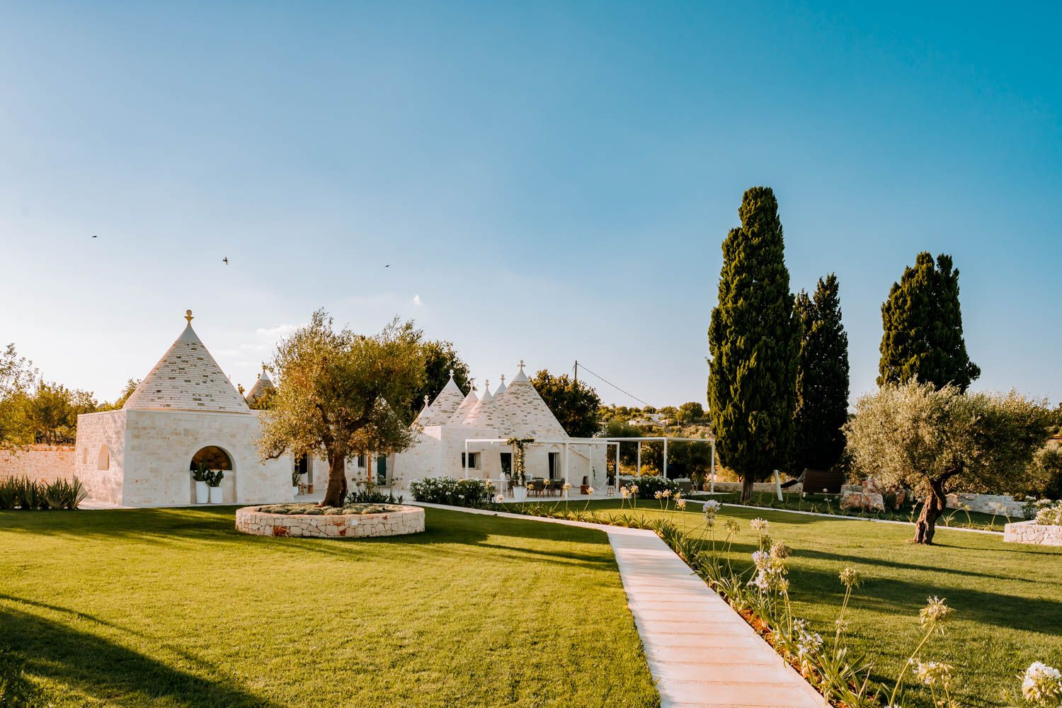 Trullo Acanto villa exterior with conical stone roofs and Mediterranean gardens, Cisternino, Puglia, Italy